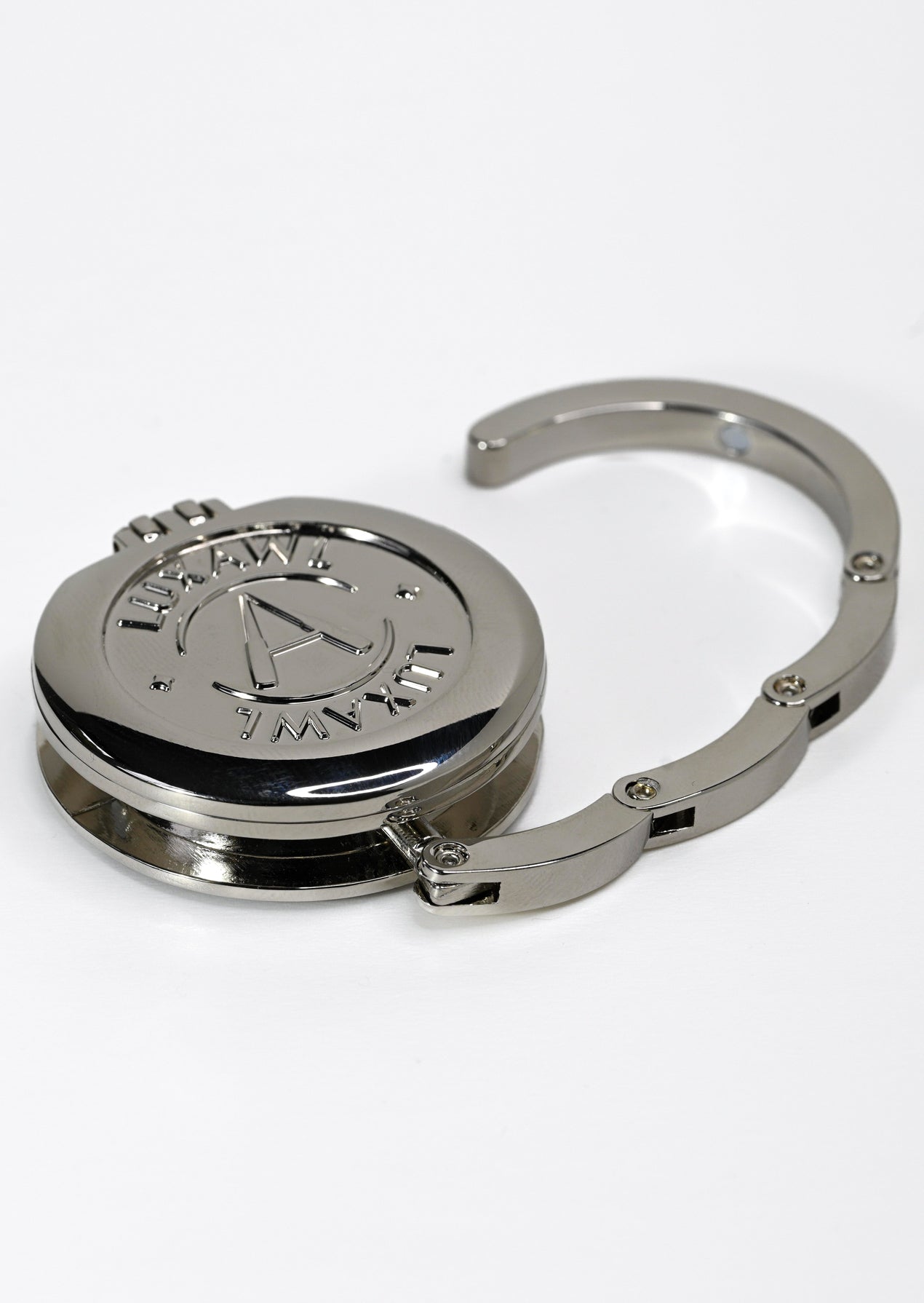 Silver purse hanger bag hook on a white surface opened out