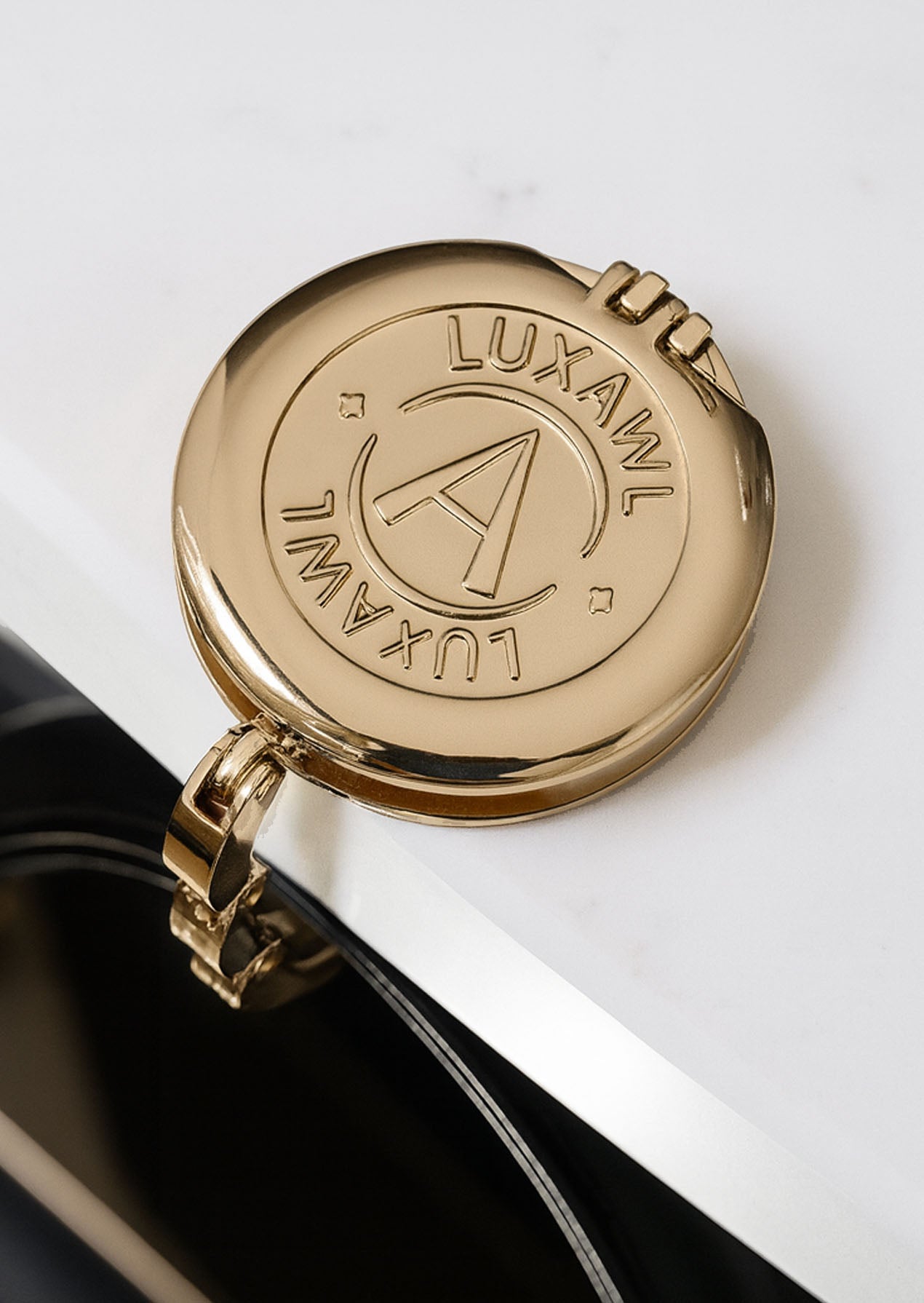 Gold LUXAWL foldable table bag hook holding a black designer bag